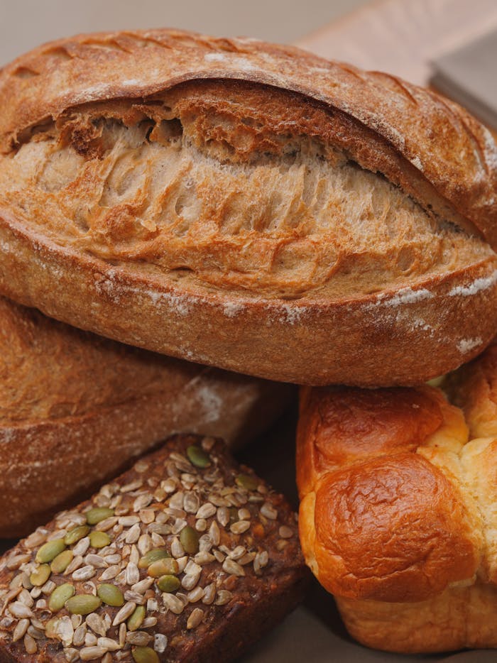 Freshly baked artisanal breads including rye, brioche, and sourdough stacked together.